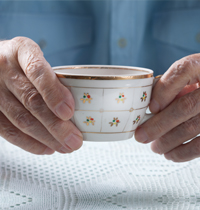 an elderly person holding a cup of tea