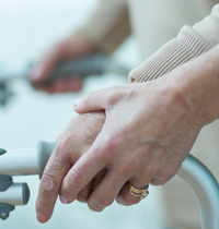 hands of two people holding on to a walker