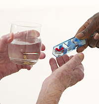 A hand holding a pill box and a glass of water