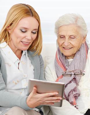 an older person with their carer looking at a tablet