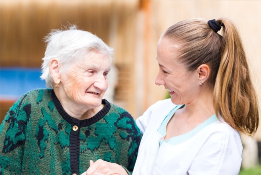 a dementia care service user and their carer smiling at each other