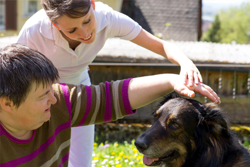A service user with their carer petting a dog
