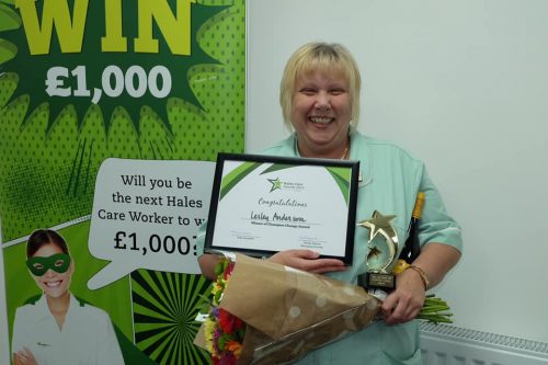 a photo of a female care worker holding a certificate and a star shaped trophy