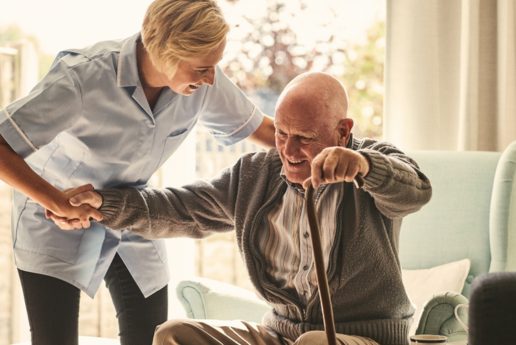 female care worker helping an elderly man with a cane