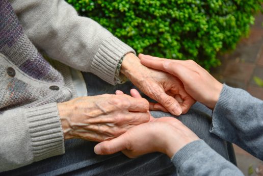 A person holding a hand of an older person