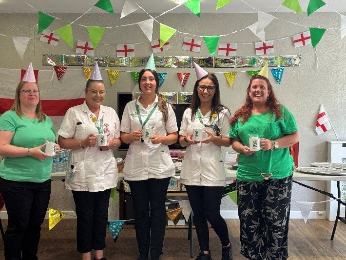 A group of female Hales carers wearing matching outfits holding cups