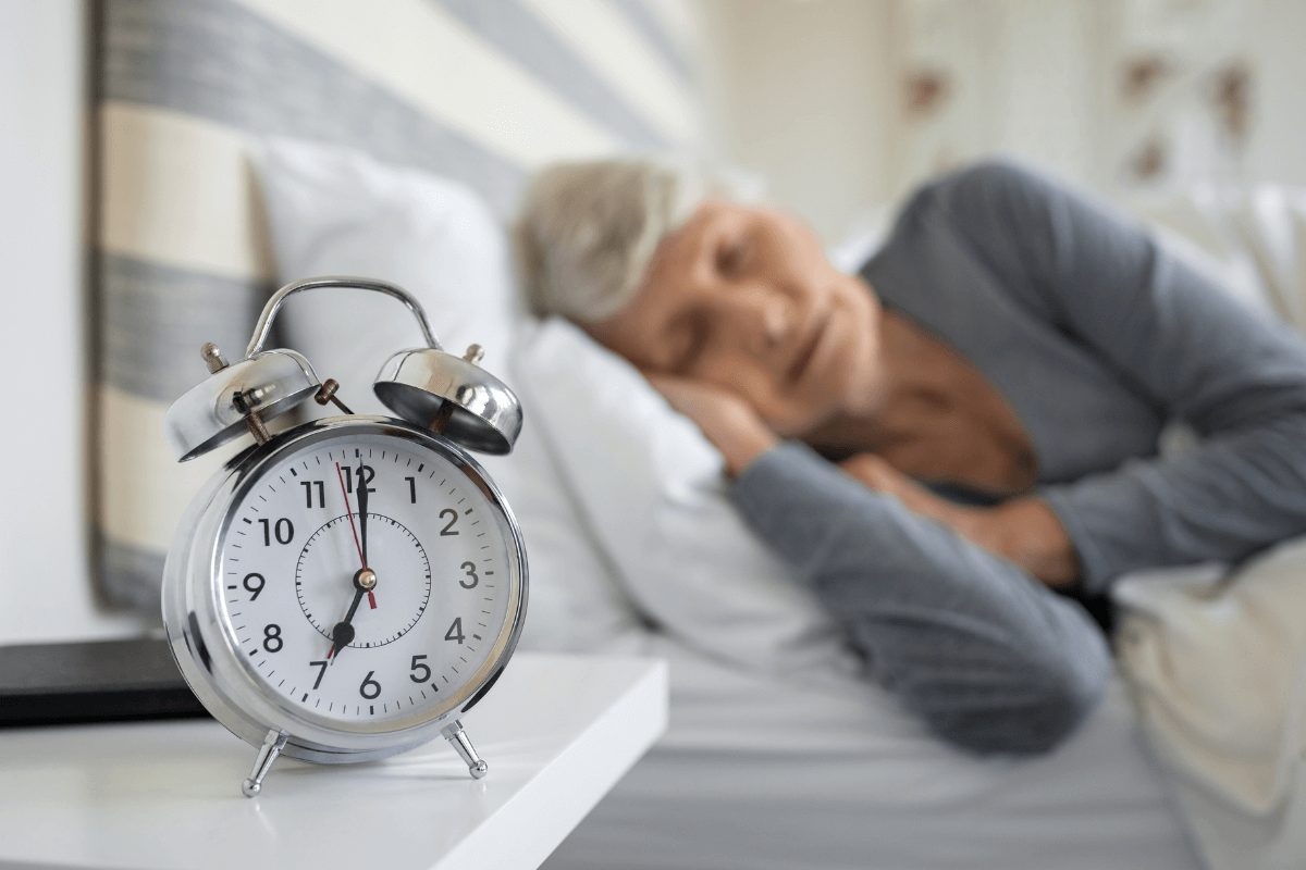 a photo of a senior woman sleeping and a clock on the bedside table